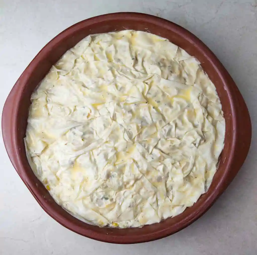 image showing how to top the last layer of phyllo sheet with sour cream mixed with eggs 