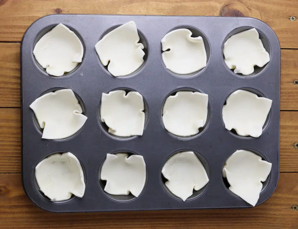 image showing how to place the pieces into a muffin tin before loading them with brie and pears 