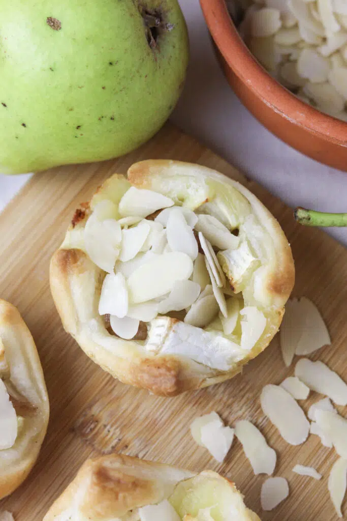 brie and pear puff pastry bite with a bowl of almond slices in the background